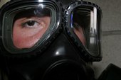 A Marine glares through the limited-spaced eye protection part of his gas mask.